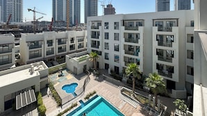 Un immeuble d’appartements moderne doté de nombreux balcons, d’une piscine sur le toit et d’une cour aménagée.