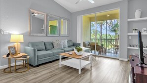 A modern living room with a grey sofa, a wooden coffee table, and a ceiling fan. - Book your Labor Day stay before dates fill up / Plus Free Night! (Kissimmee)