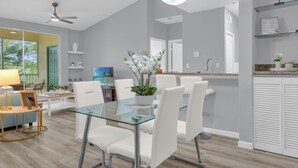 A modern kitchen with a glass dining table, white chairs, and a potted orchid. - Book your Labor Day stay before dates fill up / Plus Free Night! (Kissimmee)