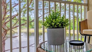 A balcony with a glass table, a potted plant, and a chair. - Book your Labor Day stay before dates fill up / Plus Free Night! (Kissimmee)