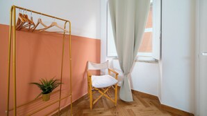 A room with a wooden chair, a metal drying rack, and a potted plant. - La Posada by Rentbeat (Civitavecchia)