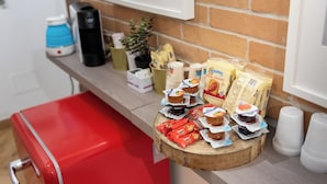 A kitchen counter with various food items, including packaged snacks, a coffee maker, and a red cooler. - La Posada by Rentbeat (Civitavecchia)