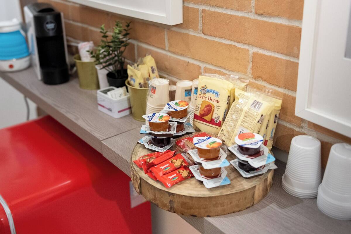 A kitchen counter with various food items, including packaged snacks, a coffee maker, and a red cooler.
