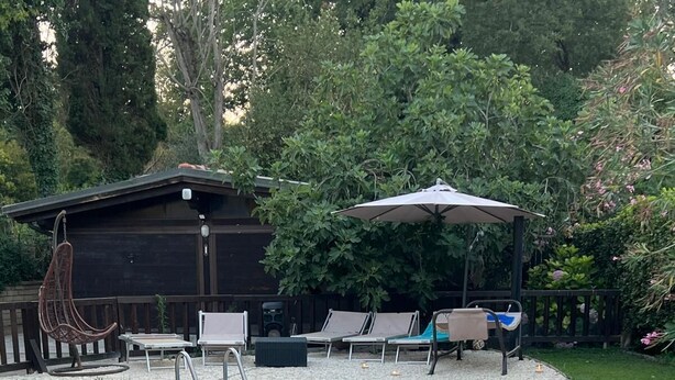 A rectangular swimming pool with a stone edge, surrounded by a grassy area and a wooden deck. - Paradise home (Rome)