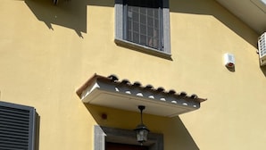 A yellow building with a wooden door, a small porch, and a welcome mat. - Paradise home (Rome)