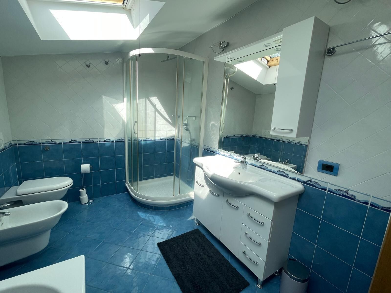 A modern bathroom with a glass-enclosed shower, a white sink, and a toilet.