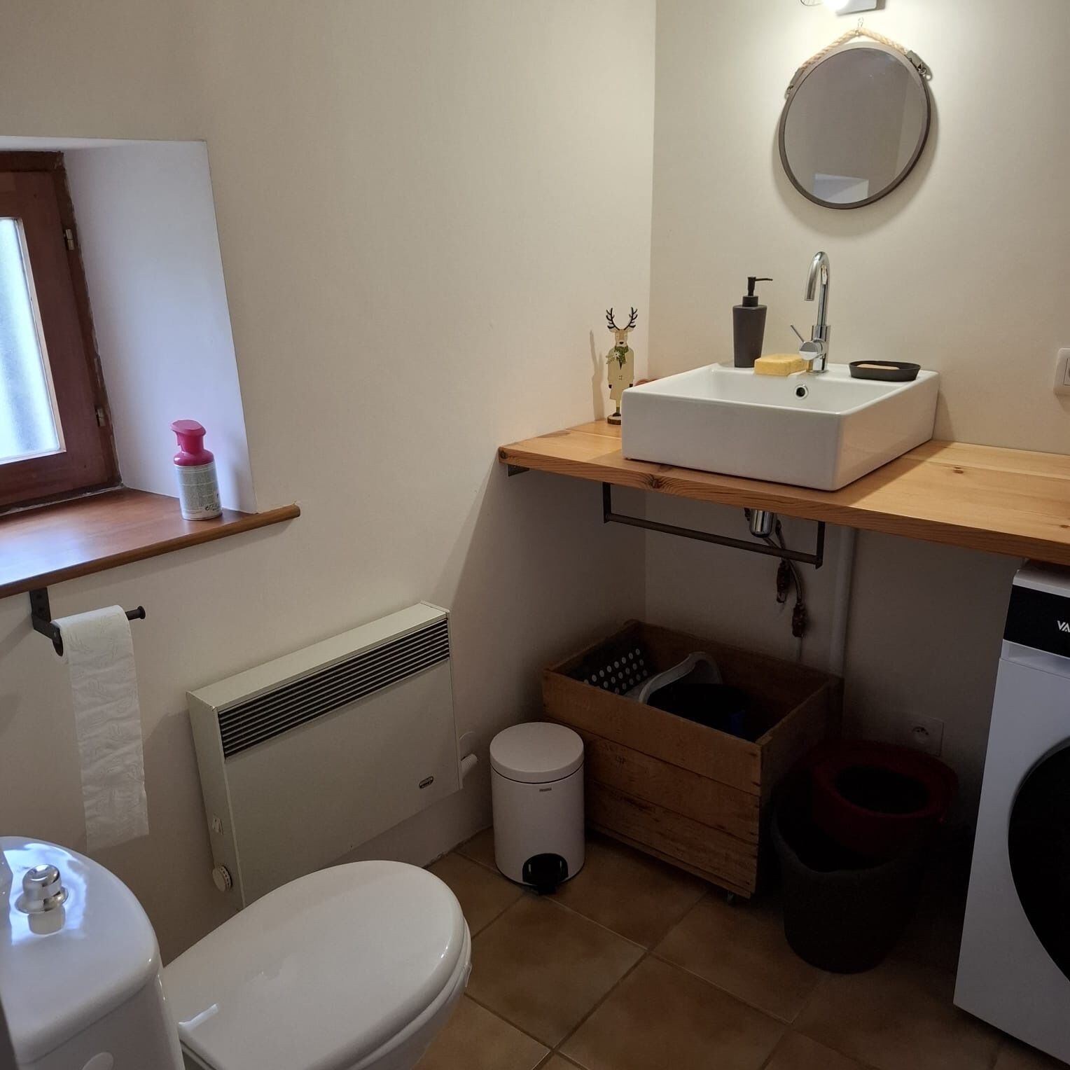 Une petite salle de bain comprenant des toilettes, un lavabo et une petite fenêtre.