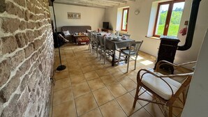 A dining area with a wooden table and chairs, a sofa, and a fireplace. - Charming traditional farmhouse, relaxation and nature (Taintrux)