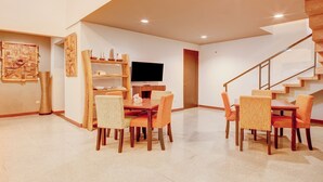 A modern dining area with a wooden table and chairs, a flat-screen TV, and a staircase. - Collection O near MRT Cipete Raya formerly Terogong Sembilan (Jakarta)