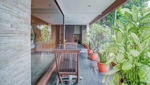 A modern outdoor seating area with a stone wall, wooden chairs, and potted plants. - Collection O near MRT Cipete Raya formerly Terogong Sembilan (Jakarta)