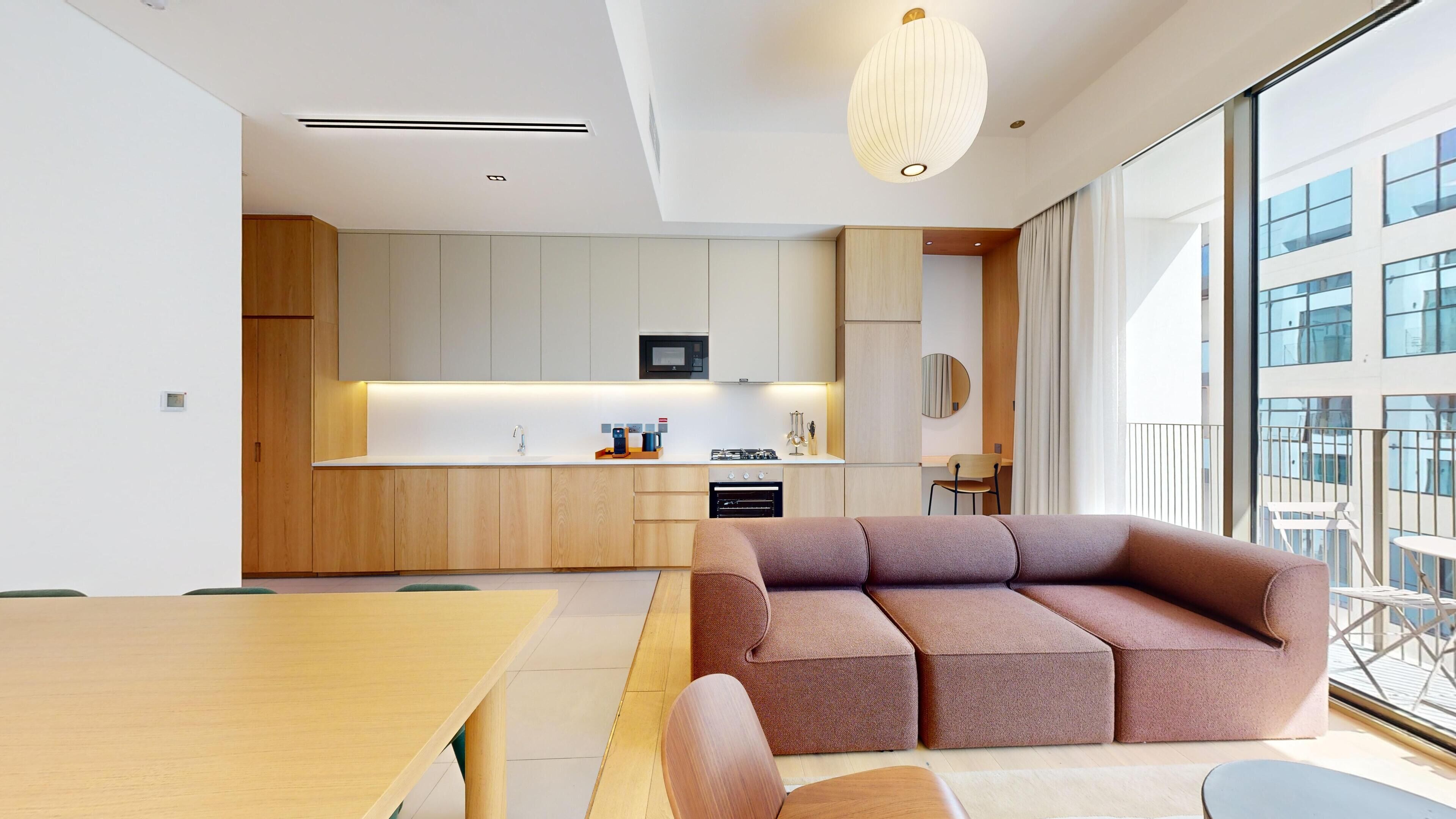 Une cuisine moderne dotée d’un îlot central, de meubles en bois et d’un four encastré.