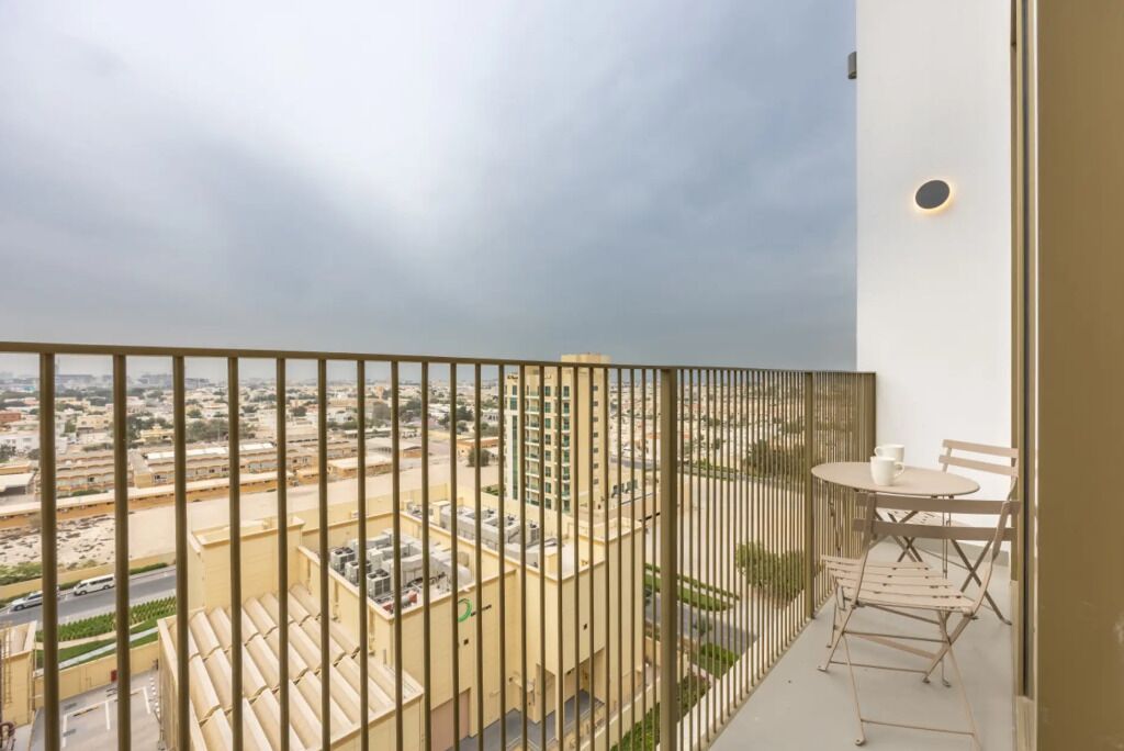 A balcony with a view of a cityscape, a table with chairs, and a small potted plant.