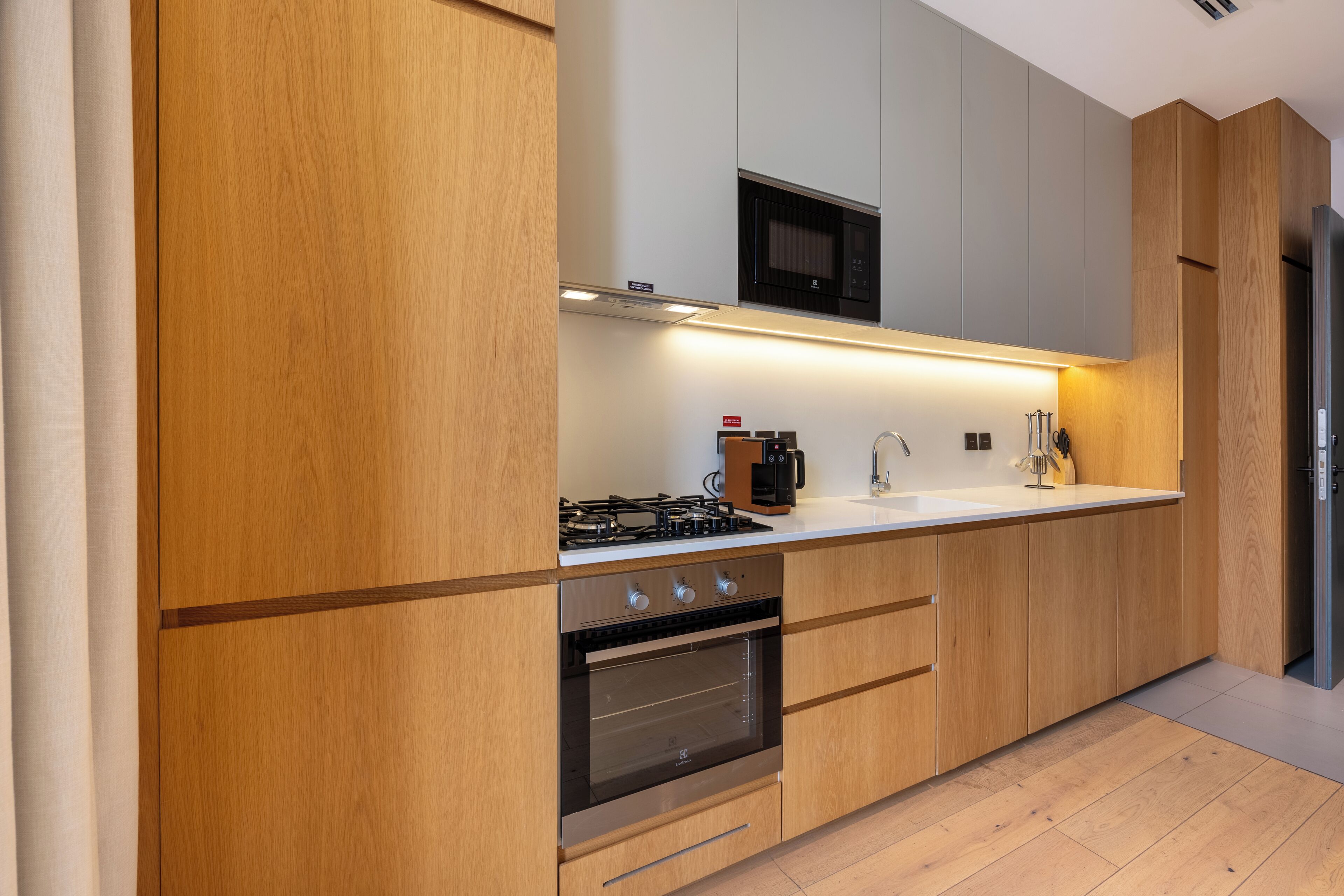 Una cucina moderna con mobili in legno, forno ventilato, microonde e piano cottura a gas.