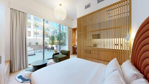 Ein modernes Hotelzimmer mit einem großen Bett, Blick auf die Stadt und einem Balkon mit Sitzgelegenheit.