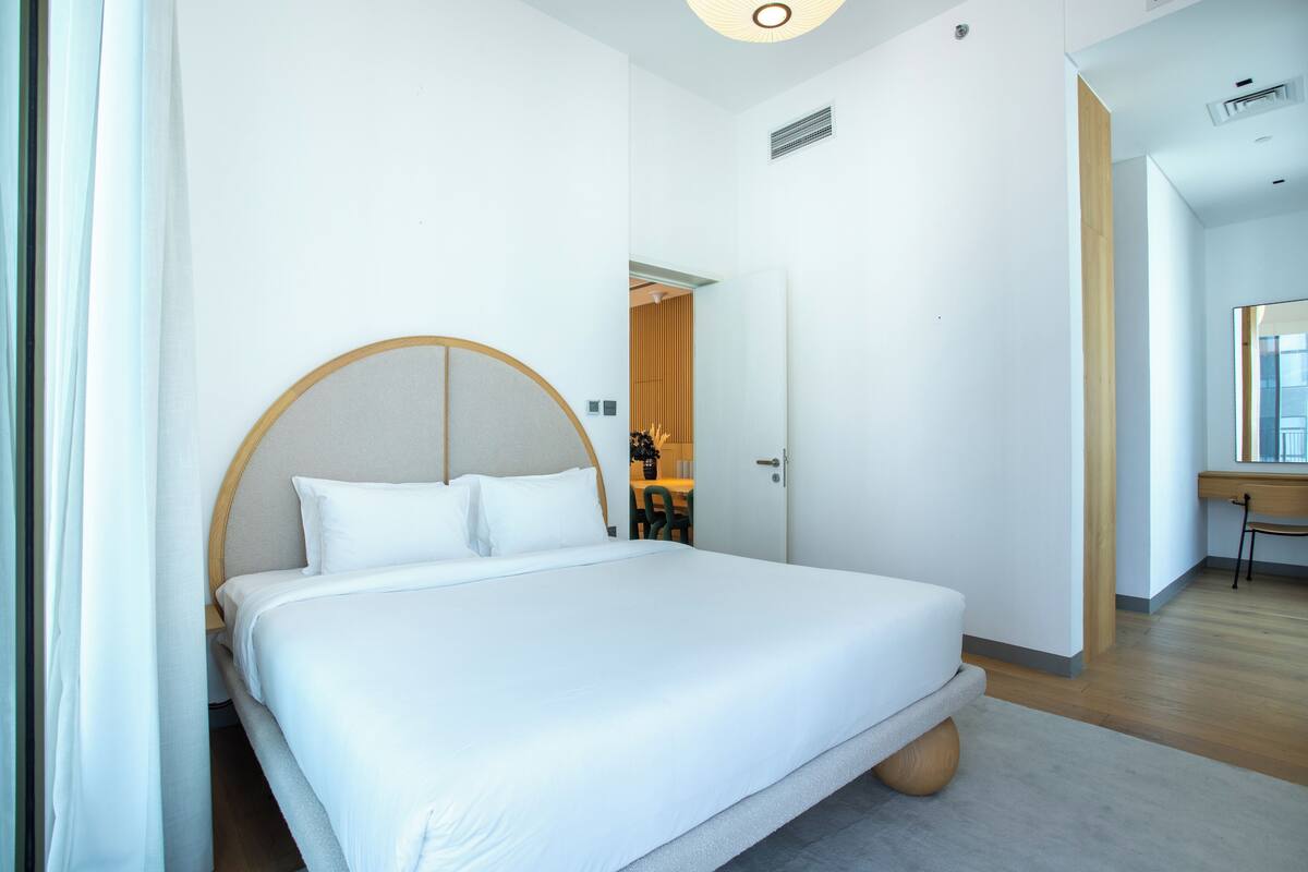 A modern hotel room with a large bed, a desk, and a chair.