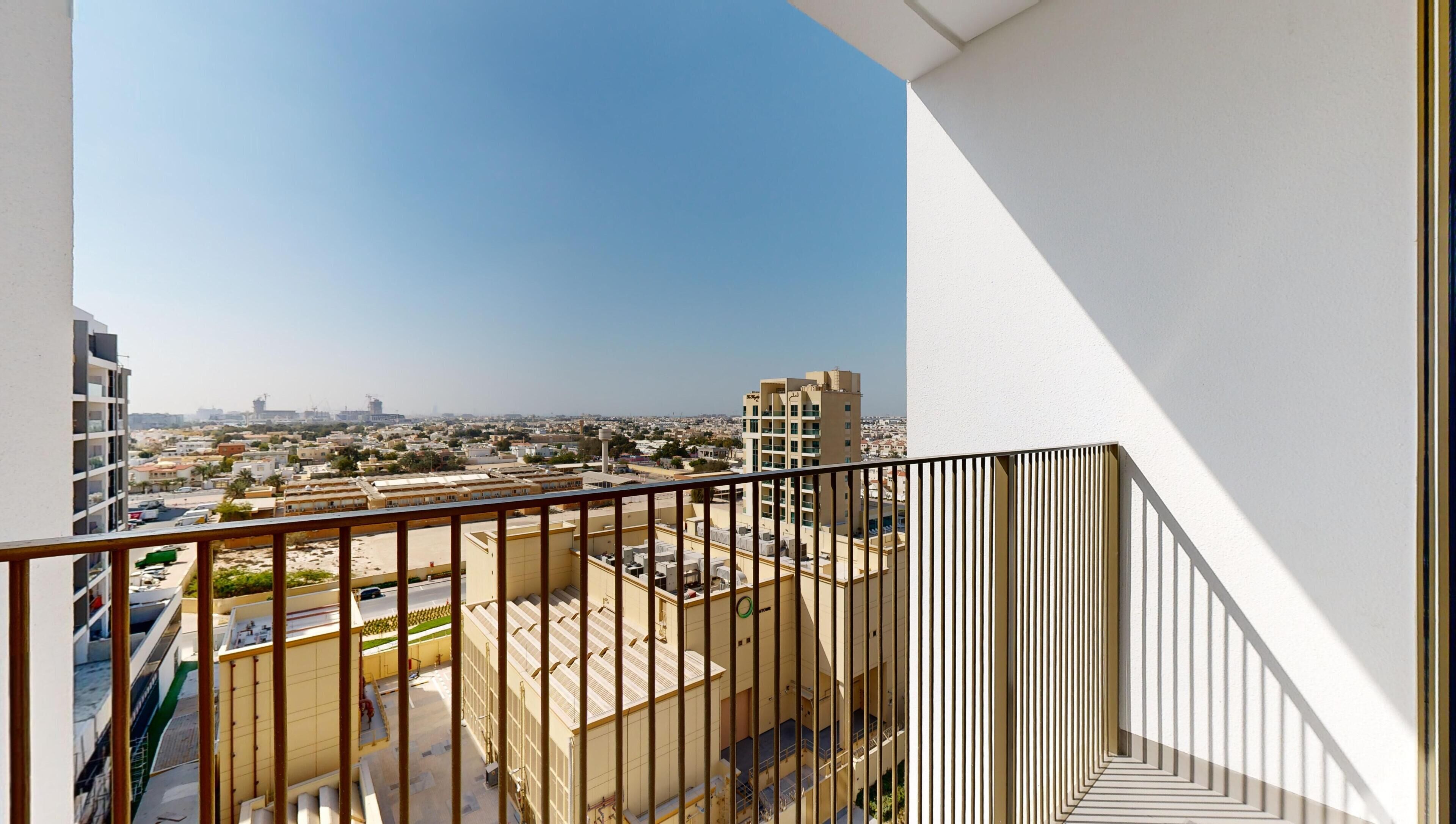 A balcony with a view of a cityscape, featuring a mix of residential and commercial buildings.