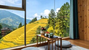 Habitación con un amplio ventanal con vistas a campos escalonados y montañas.
