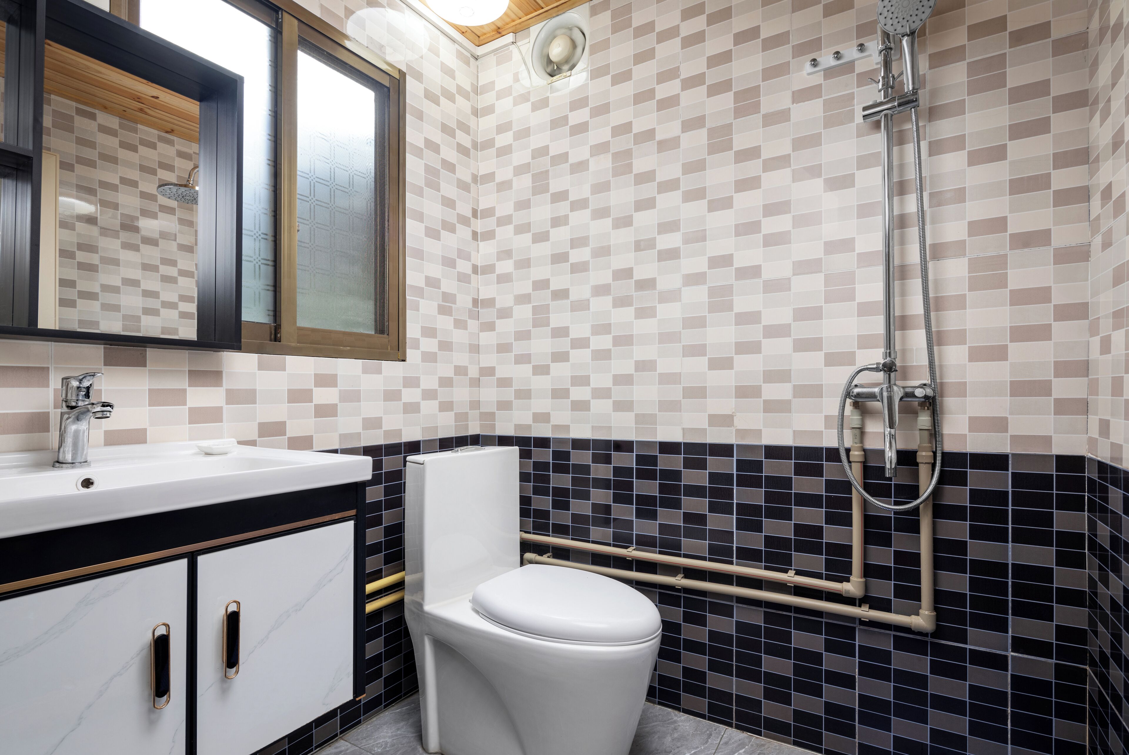 A bathroom with a white toilet, a sink with a mirror above it, and a shower with a tiled wall.
