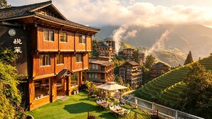 Un edificio de madera tradicional con terraza, rodeado de campos escalonados y montañas.