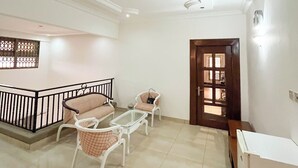 A spacious living area with a balcony, a sofa set, a coffee table, and a wooden door leading to another room. - Parry Suite (Weija)