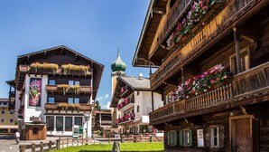 A traditional wooden building with balconies adorned with flowers, a green dome, and a sign for a cafe. - Mountain & Golf Resort Westendorf (Westendorf)