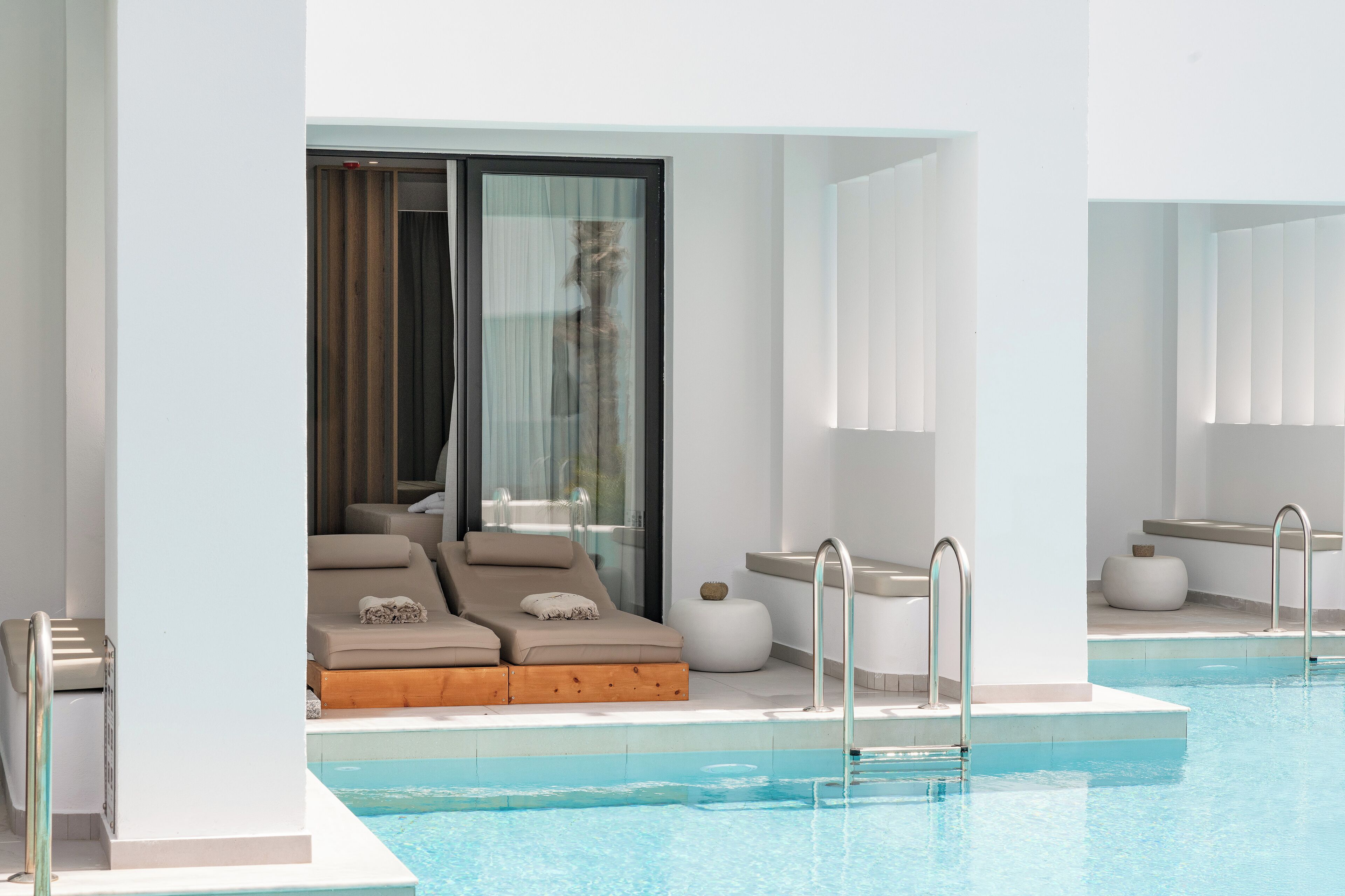 A modern pool area with a glass-enclosed lounge, a pool with clear blue water, and a minimalist design.