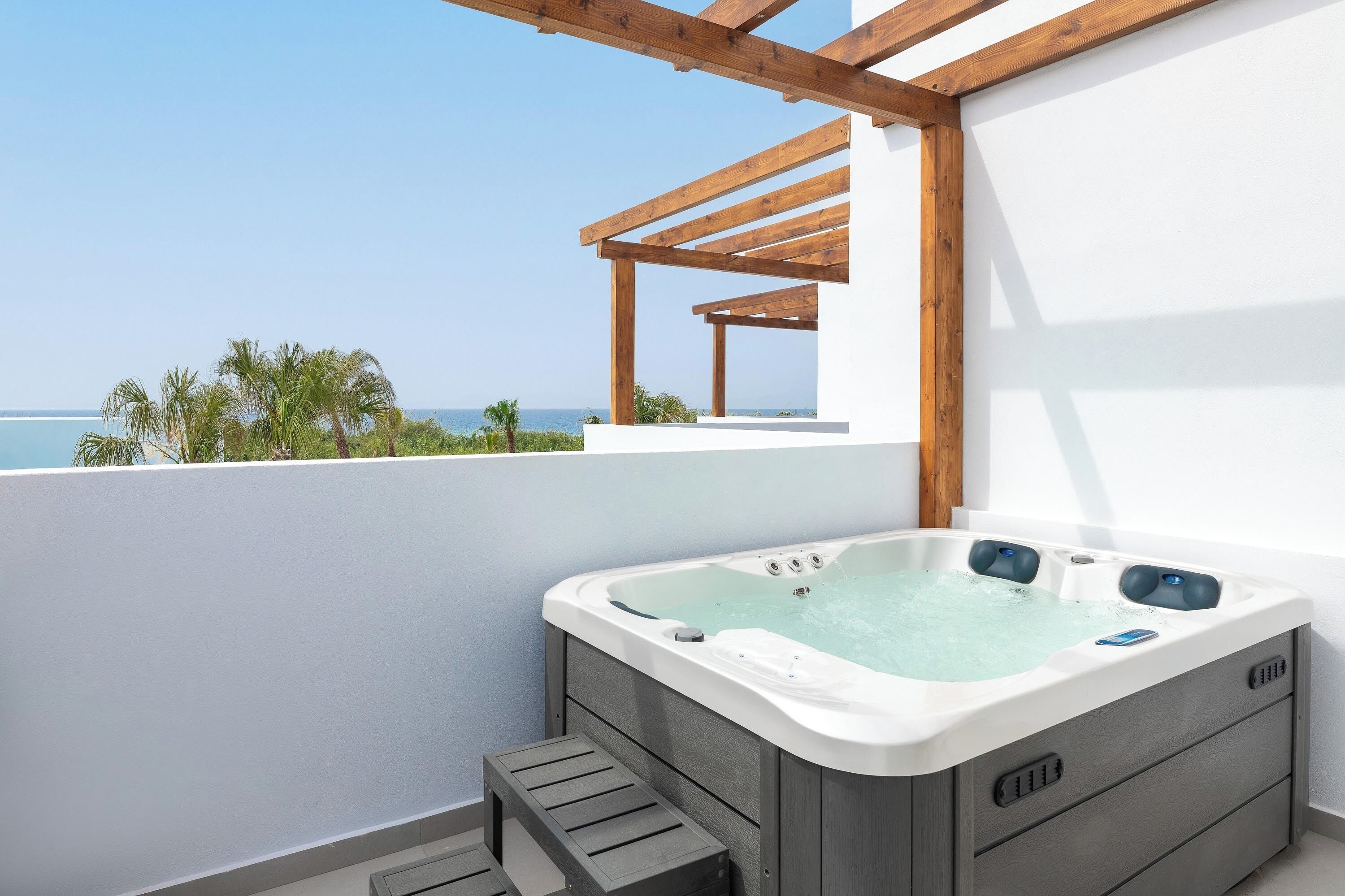 A hot tub on a balcony with a clear view of the sea.