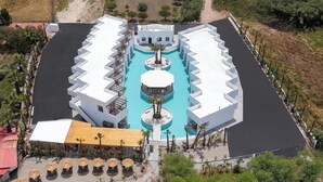 An aerial view of a resort with a central swimming pool, multiple white buildings, and outdoor seating areas.