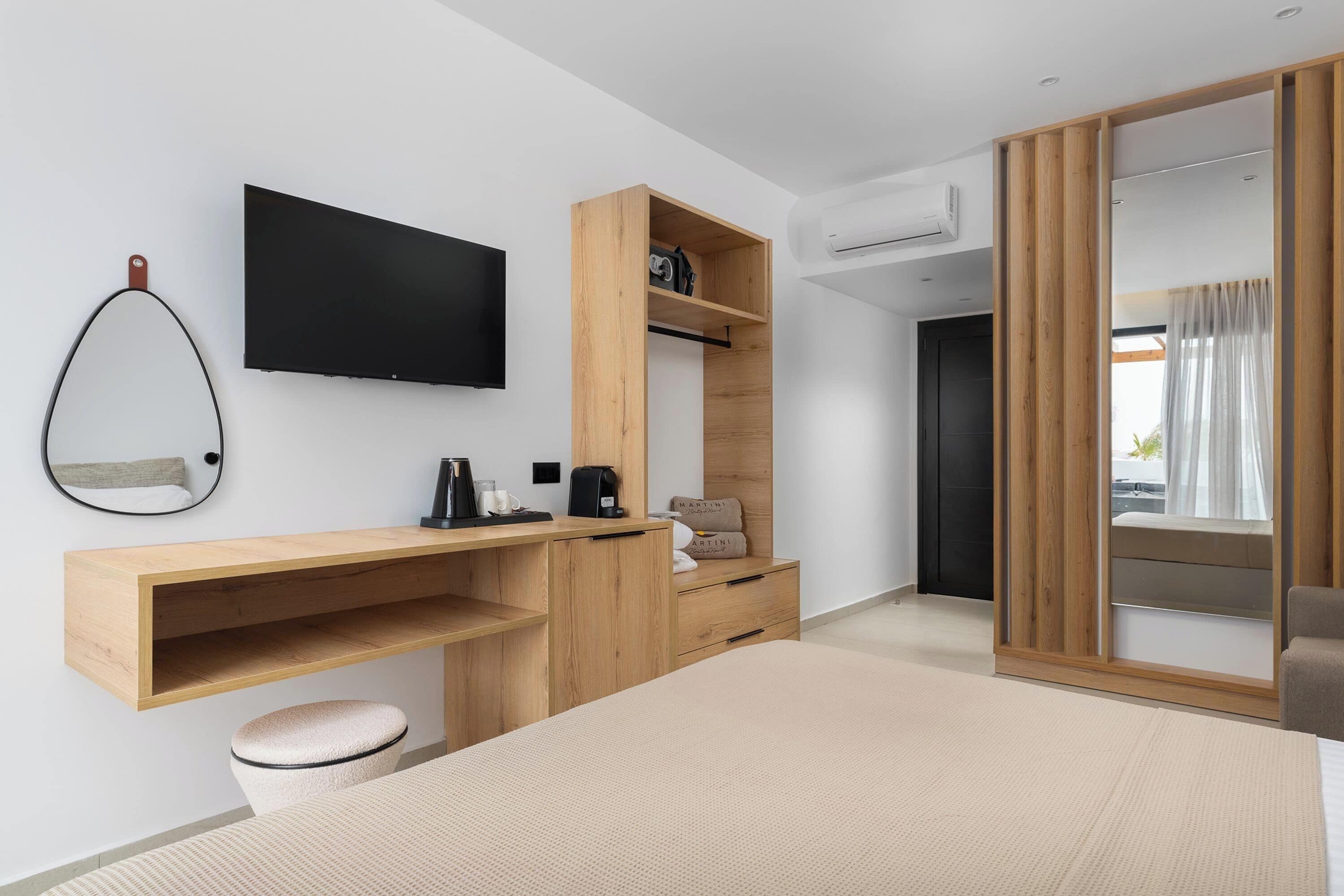 Un dormitorio moderno con una cama, un escritorio de madera, un televisor y un armario.