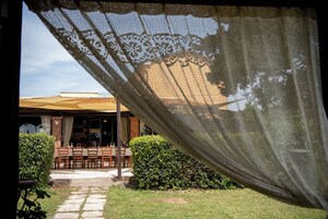 A patio area with a table and chairs, a covered seating area, and a hedge.