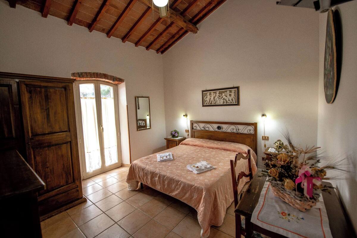 A bedroom with a wooden bed, a nightstand, a dresser, and a window with a view.