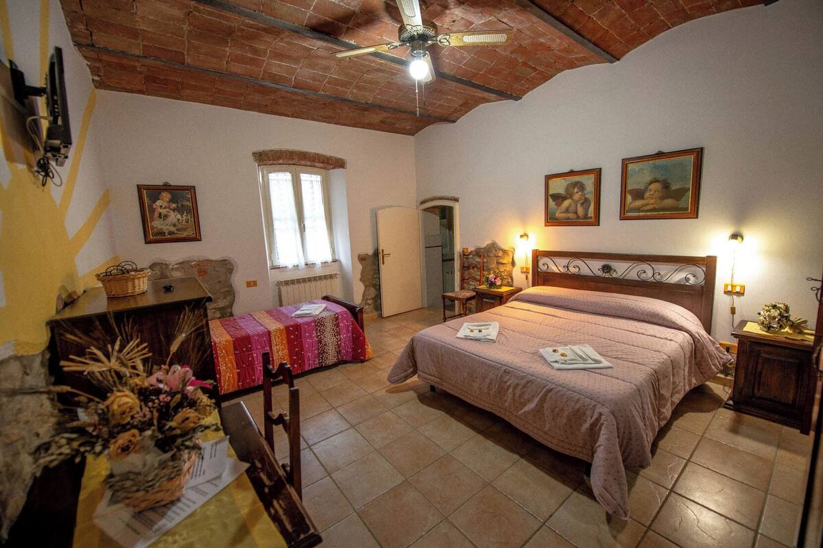 A bedroom with a bed, a desk, a chair, a window, and a door.