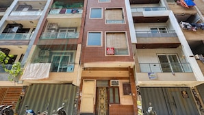 A multi-story building with balconies, a visible sign for a hotel, and a closed shuttered entrance.