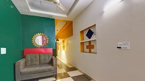 A hallway with a checkered floor, a grey sofa, a mirror, and a ceiling fan.