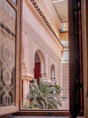 An interior courtyard with ornate arches and detailed wall patterns, featuring a palm tree and a red door. - Riad Mayan & Spa (Marrakech)