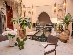 A courtyard with a table, chairs, a cactus, and potted plants. - Riad Mayan & Spa (Marrakech)