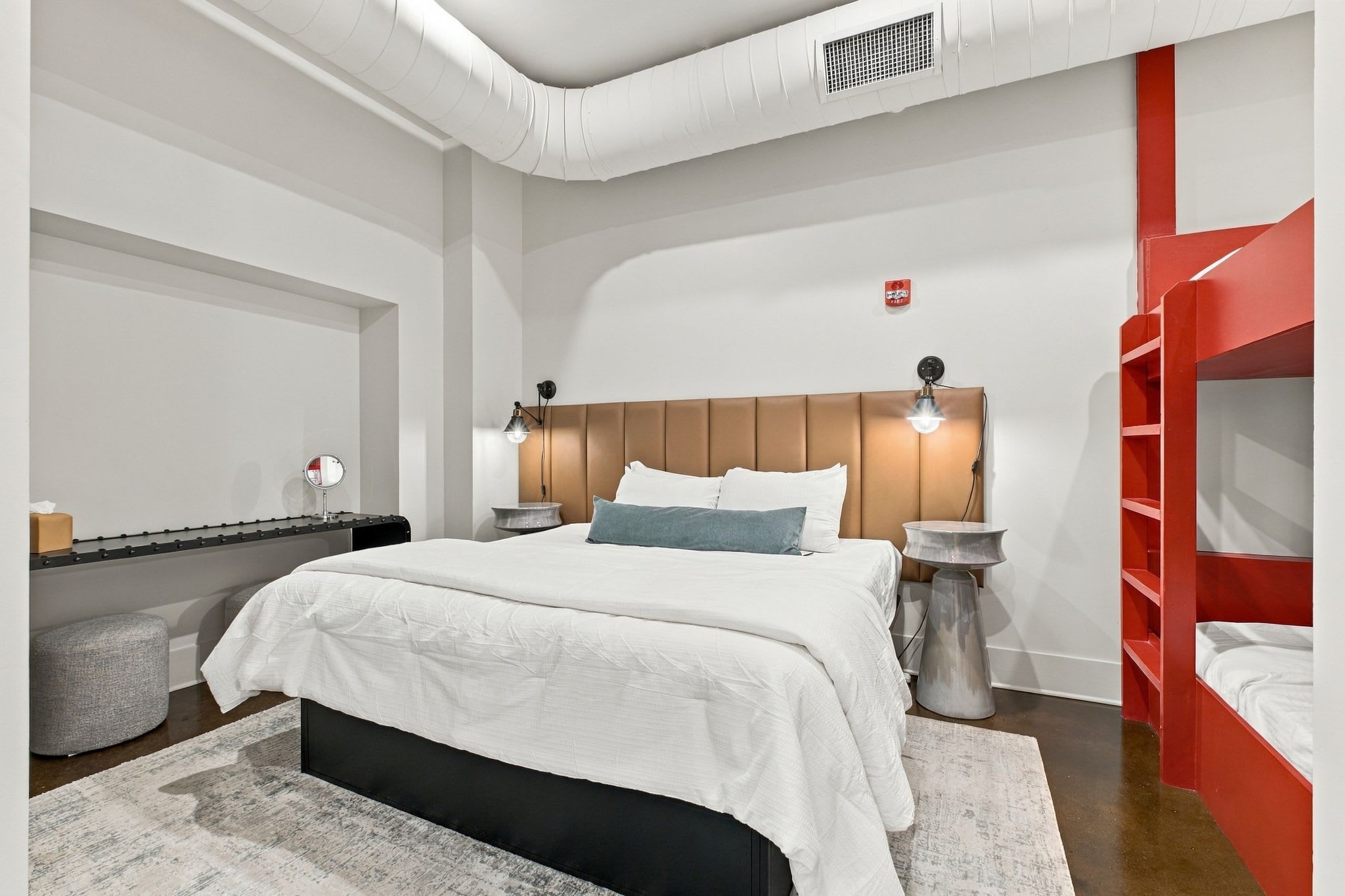 Une chambre moderne avec un lit, des tables de chevet, un miroir et un lit superposé rouge.