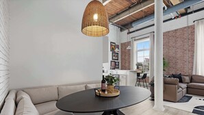 Una sala de estar moderna con una mesa redonda, un sofá y una lámpara colgante de mimbre.