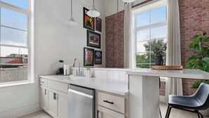 Una cocina moderna con armarios blancos, lavavajillas integrado y un amplio ventanal con vistas al exterior.