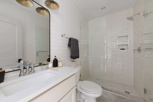 A modern bathroom with a white sink, mirror, and toilet.