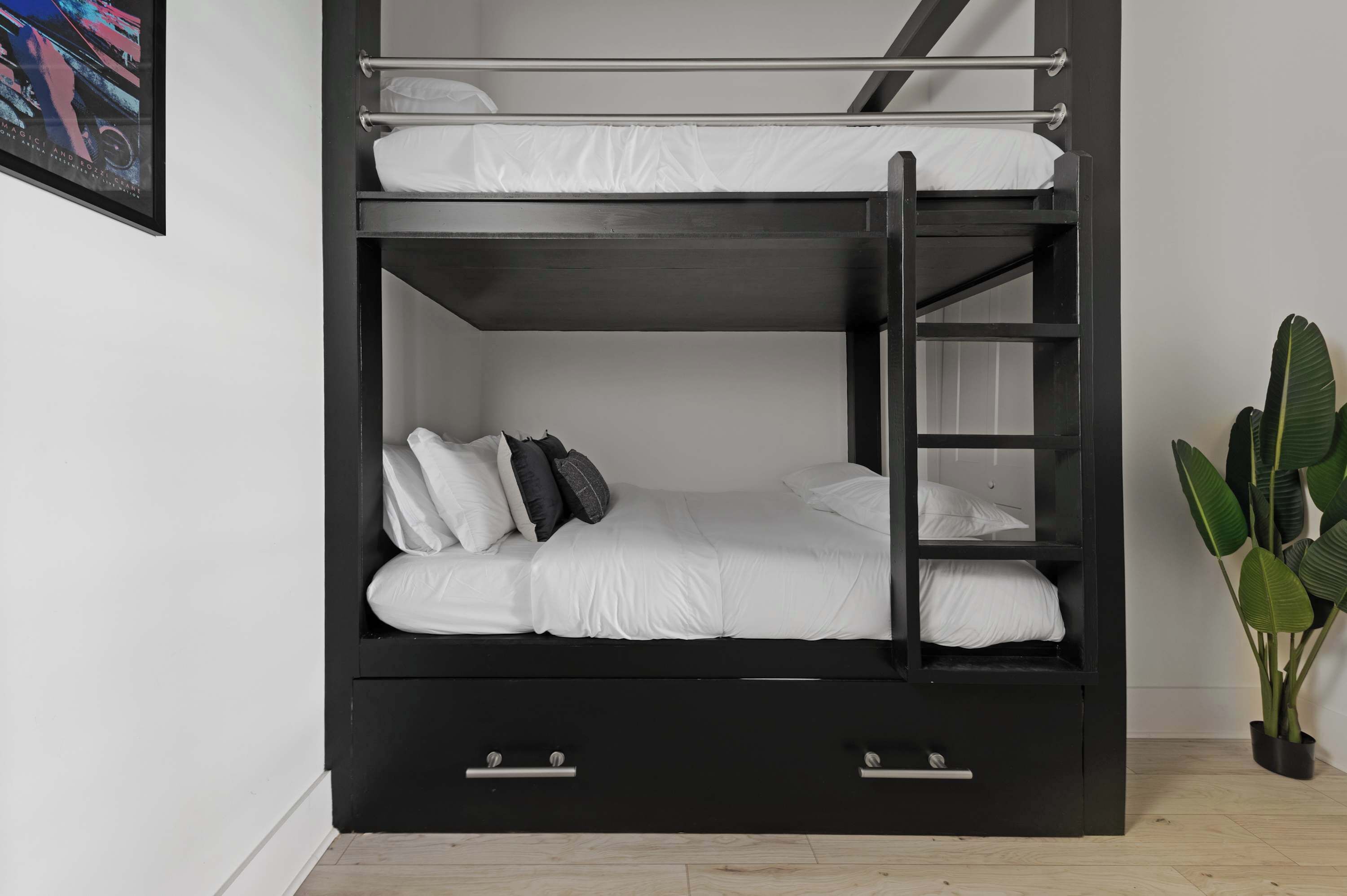 Un lit superposé avec une échelle, du linge de lit blanc et deux tiroirs.