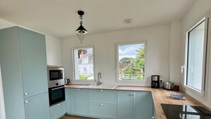 Una cocina moderna con armarios azul claro, encimera de madera, microondas integrado y ventana con vistas al exterior.
