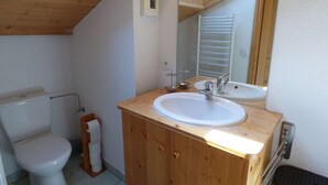 A bathroom with a wooden vanity, two sinks, a toilet, and a mirror.