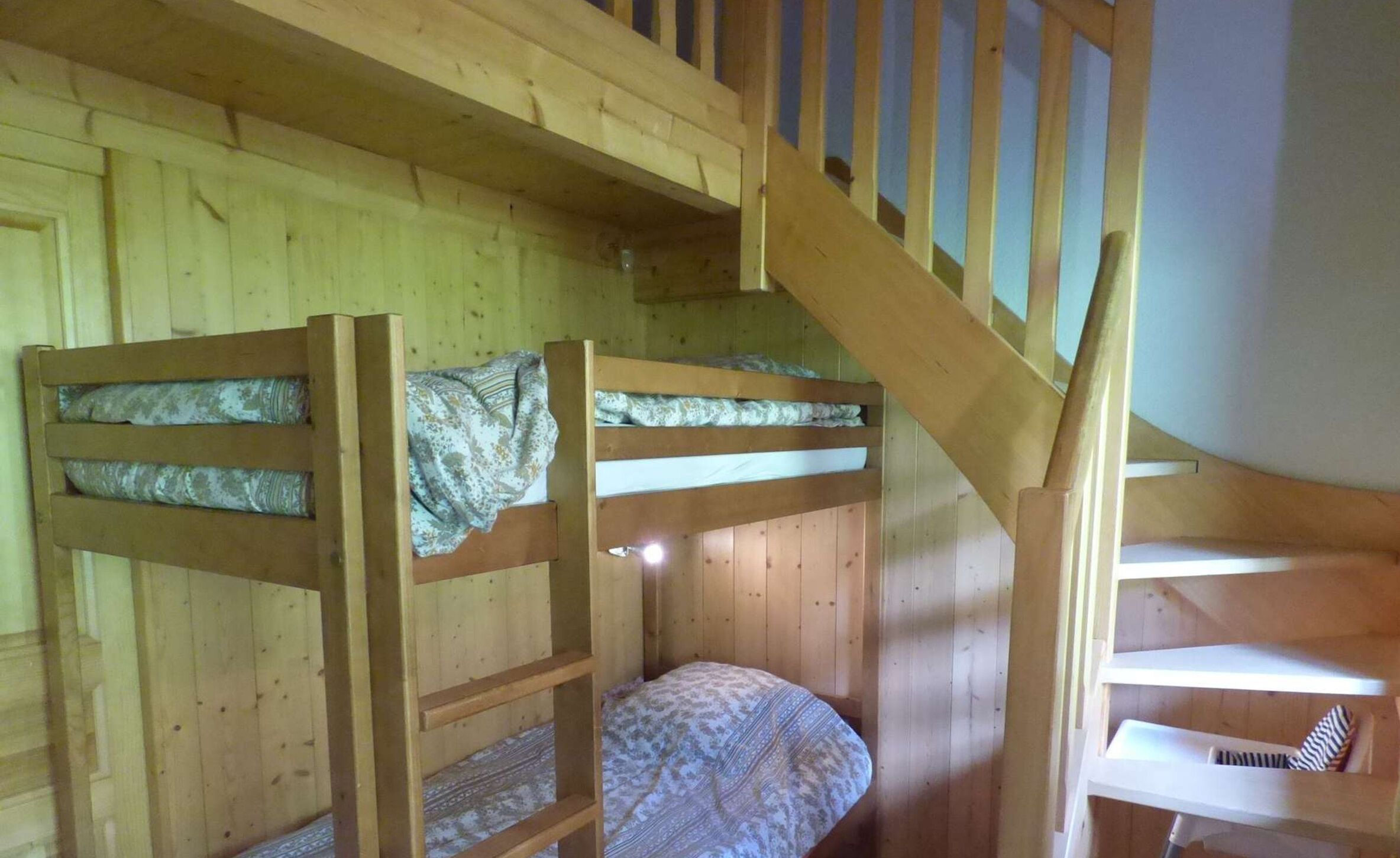 A wooden cabin with bunk beds and a staircase.