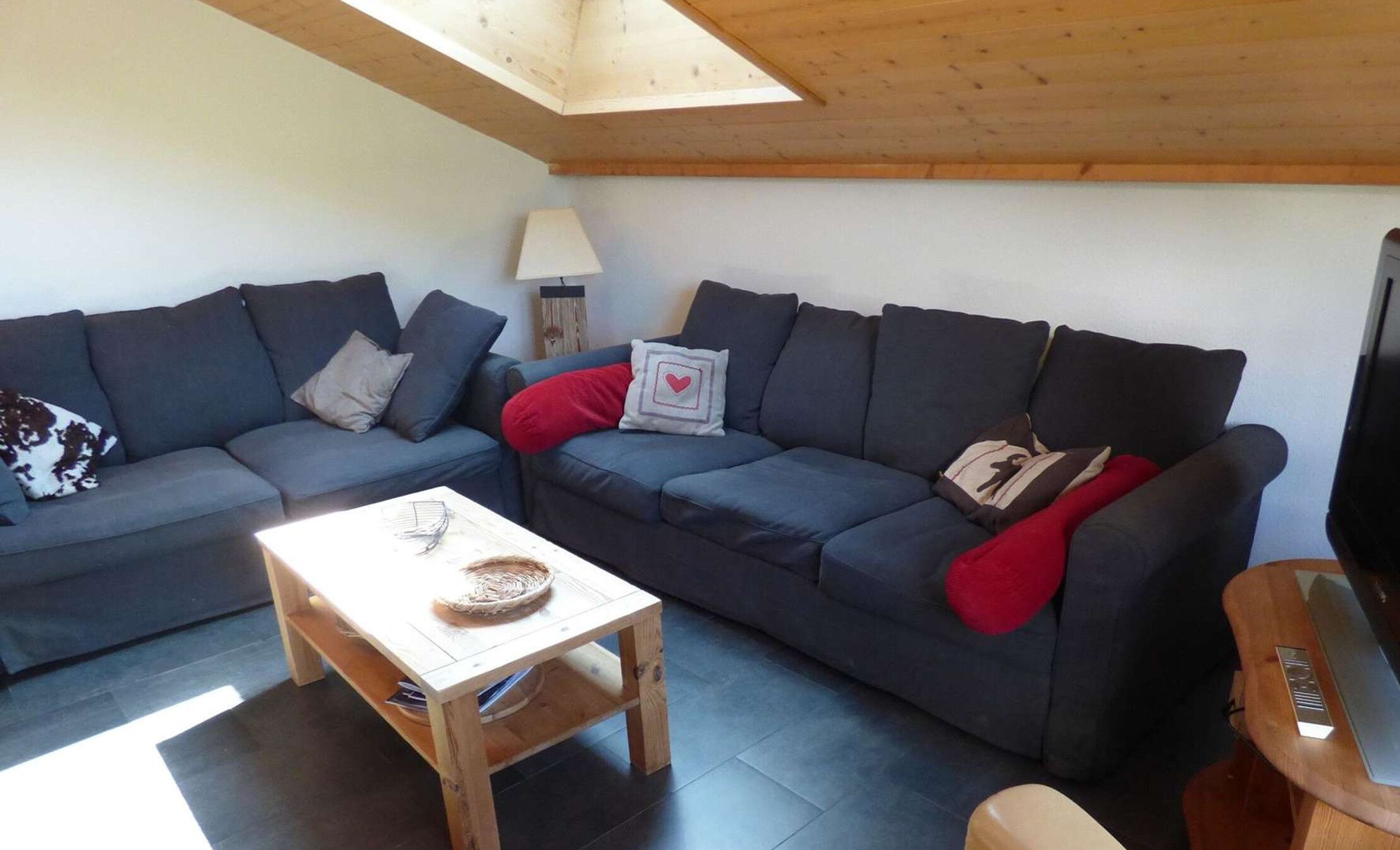 A living room with two dark sofas, a small wooden table, and a TV stand.