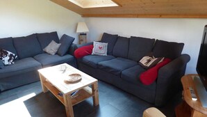 A living room with two dark sofas, a small wooden table, and a TV stand.