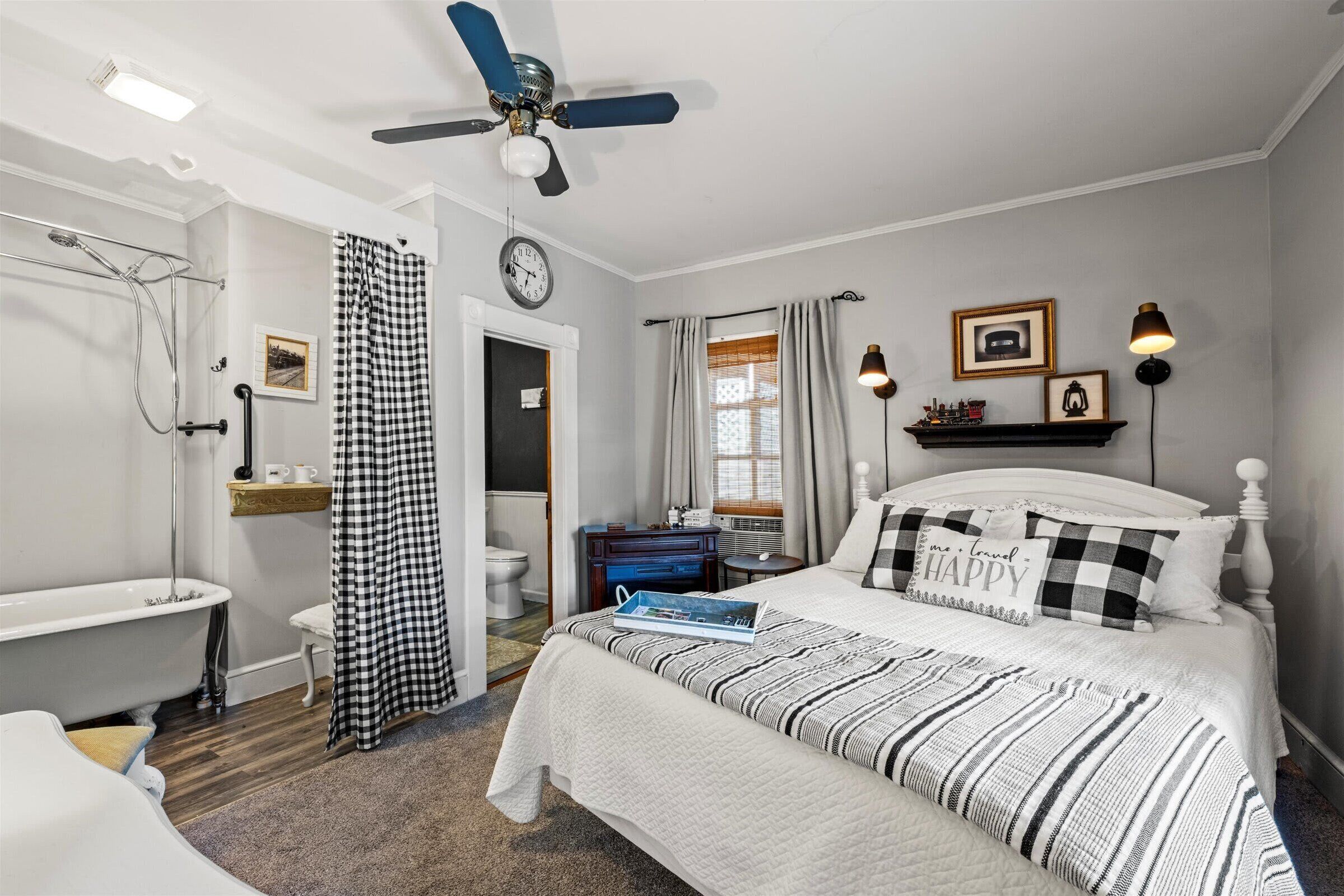 Een slaapkamer met een bed, een kaptafel, een douche en een plafondventilator.