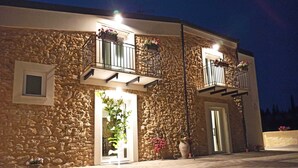 Un edificio de piedra con balcones, una puerta y plantas en macetas.