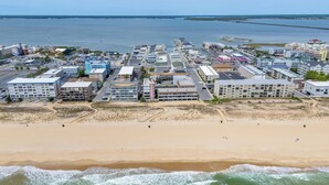 A coastal hotel with multiple buildings, a beach in the foreground, and a pier in the background. - Cozy Oceanblock Condo - Steps To The Beach (Ocean City)