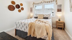 A bedroom with a bed, bedside tables, a window, and wall decorations. - Cozy Oceanblock Condo - Steps To The Beach (Ocean City)